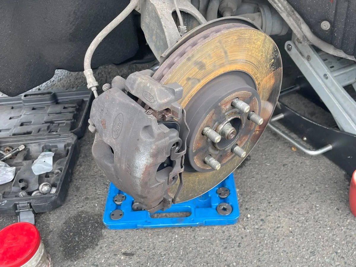 The front brake stripped down, with the caliper off the disc and hanging clear on the suspension