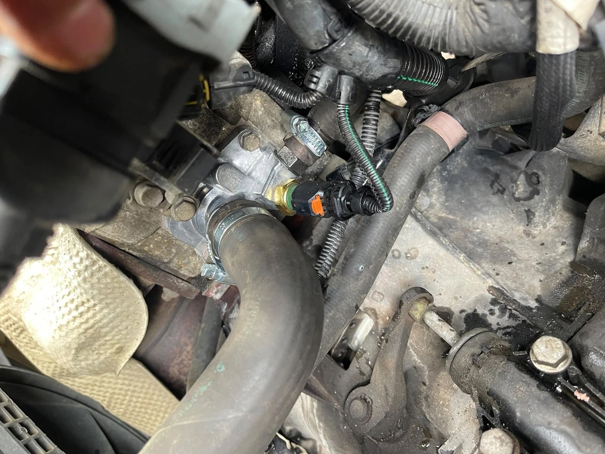 The new thermostat housing bolted on, with the coolant hose clamped back up and the sensor plug reconnected