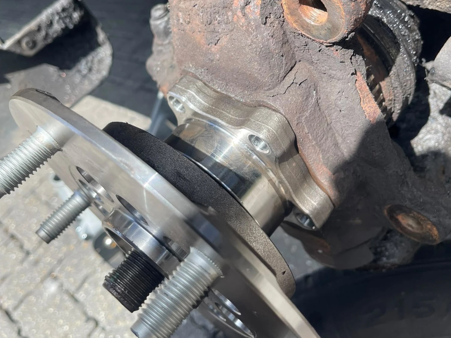 A new steel wheel hub assembly fitted against the heavily corroded original knuckle