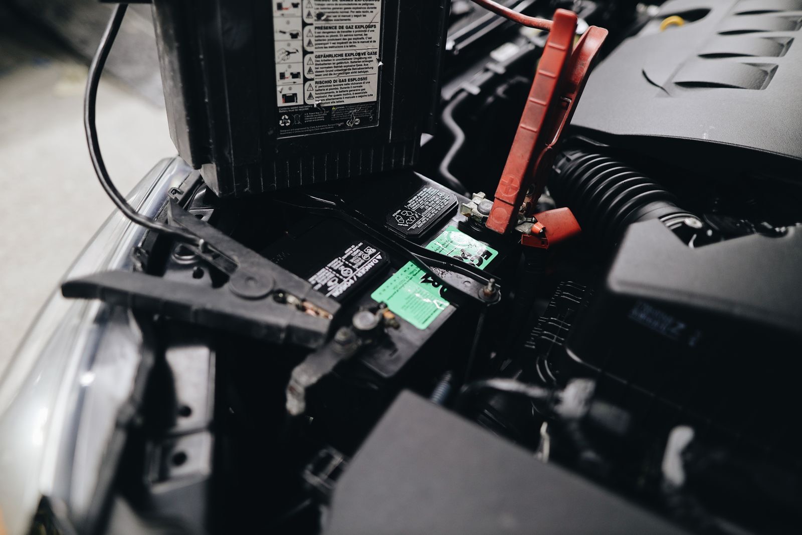 Mobile mechanic fitting a new car battery under the bonnet on a driveway