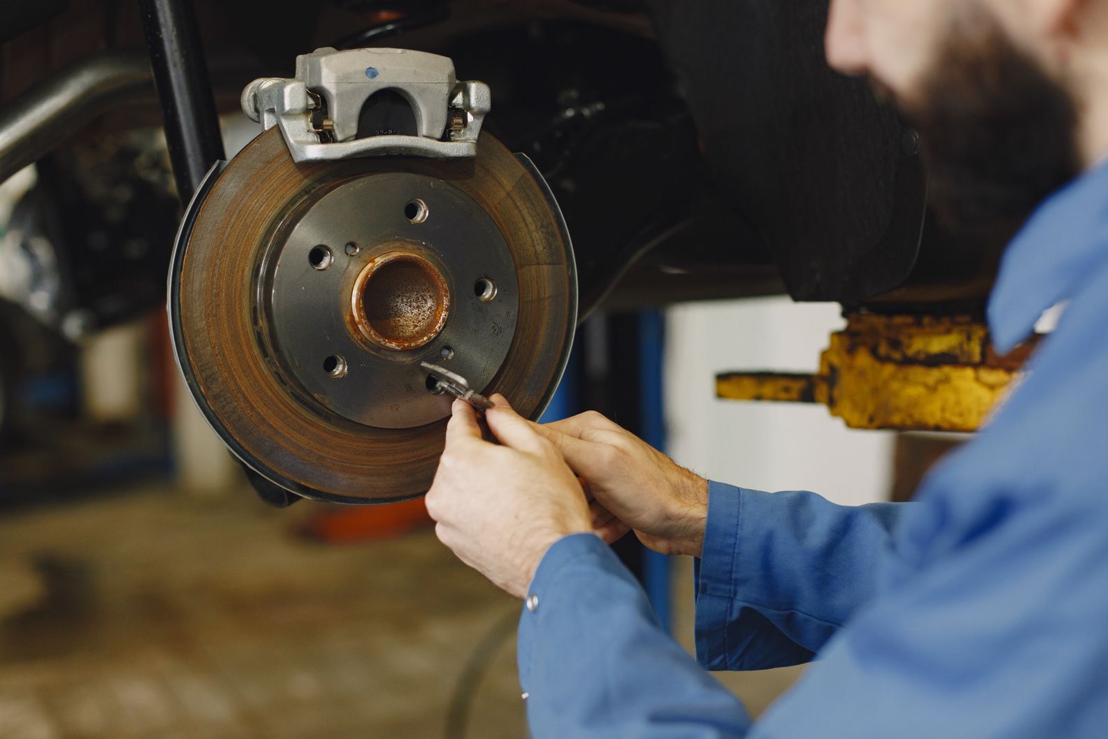 Mechanic replacing brake pads and a disc on a car wheel hub