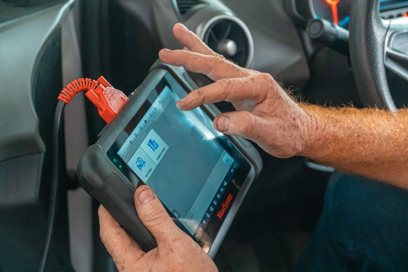 Mechanic plugging a diagnostic scanner into a car's OBD port to read fault codes