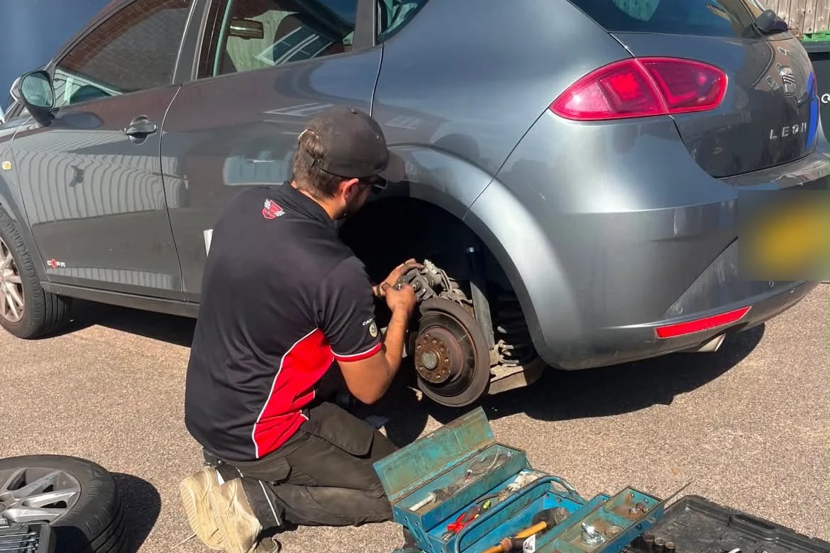 James Snow of SV Autos working on a car's rear brakes, wheel off, on a customer's driveway