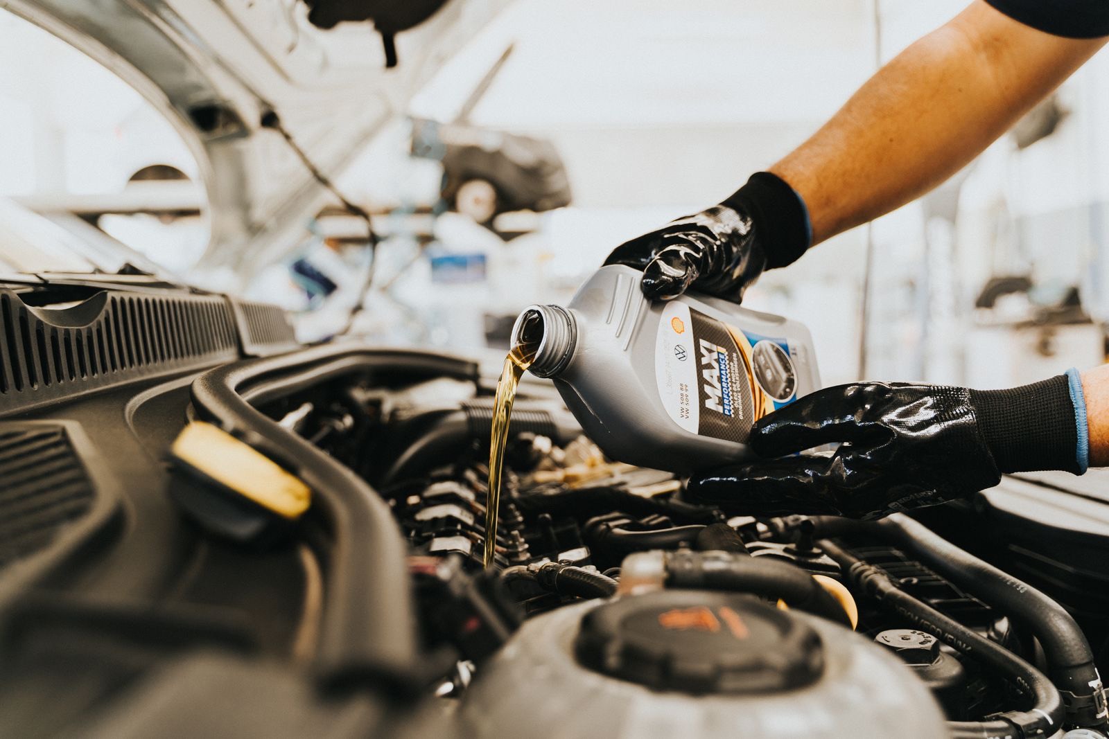 Mobile mechanic pouring fresh oil during a car service on a driveway